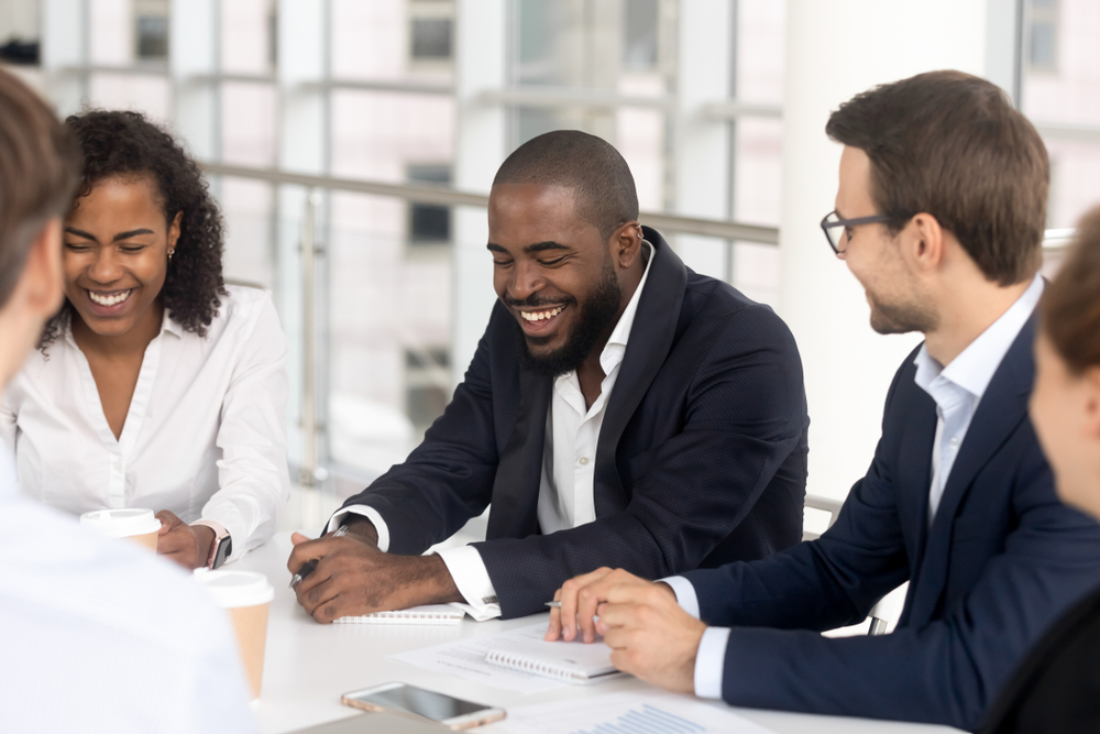Business professionals smiling together at a conference table.