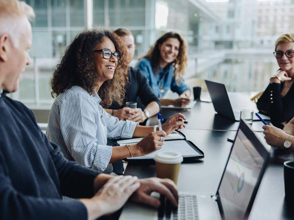 Team laughing at boardroom table building company culture